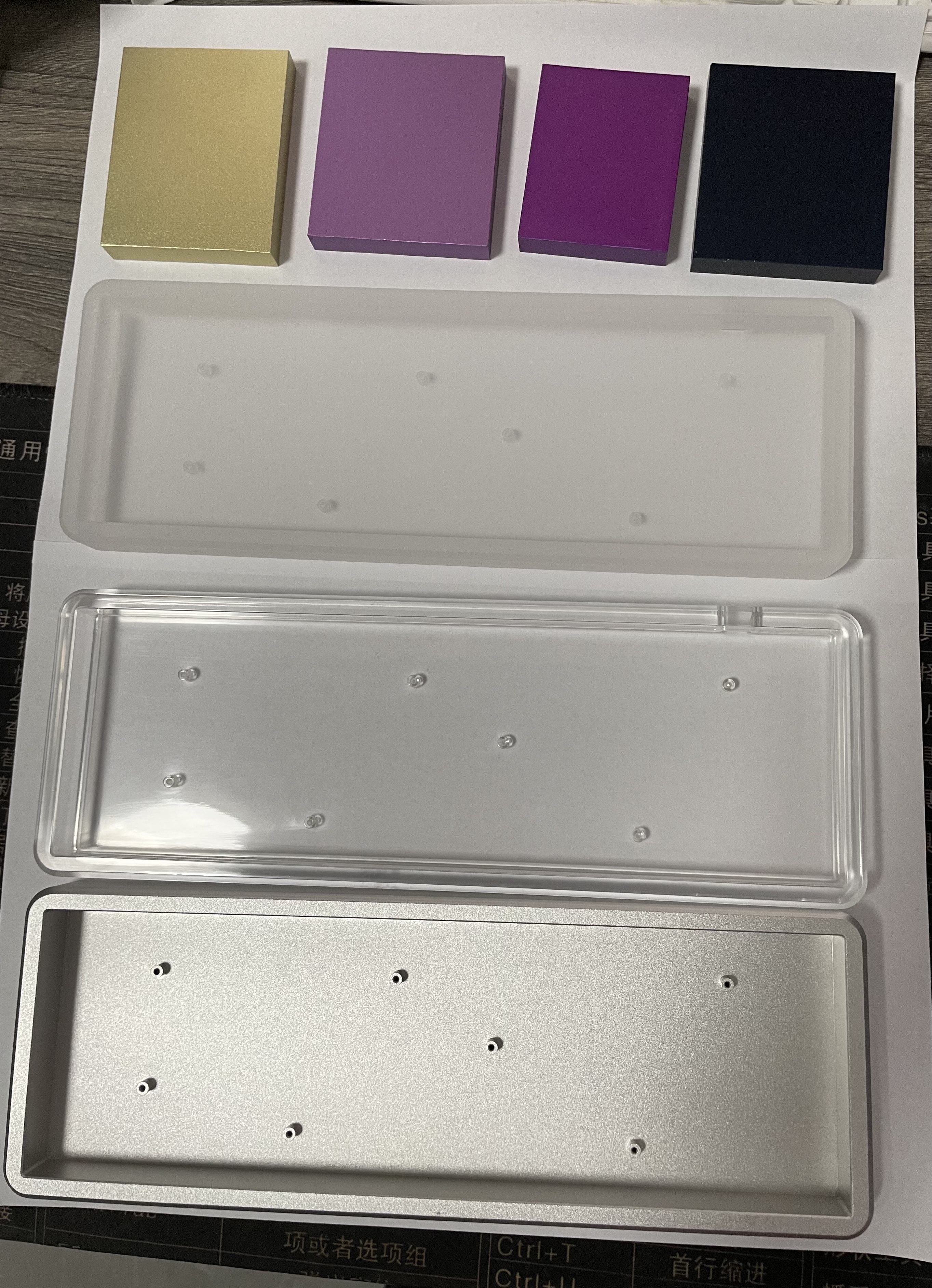 Three 2nd revision prototype MFR cases - frosted acrylic, clear acrylic, and clear anodized aluminum. Four samples for other anodization colors are also pictured.