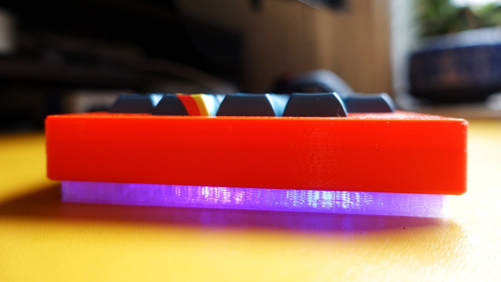 Side profile of V4N² with a red top installed. Underglow from the Monorail PCB is visible through the clear 3D printed bottom piece.